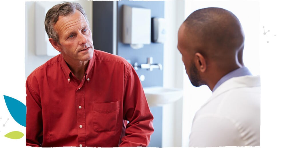 Muž v červené košili, trpící syndromem dráždivého tračníku, mluví s lékařem