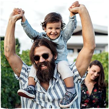 Muž v pruhovaném tričku nosí dítě na ramenou