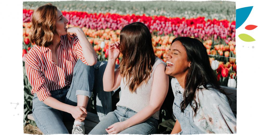 Tři dívky sedící na lavičce se smějí